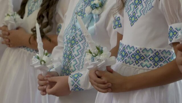 communion children hold candles,in white clothes children stand in the church at the first communion