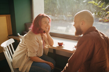 Happy couple having conversation while drinking coffee in cozy coffeehouse.