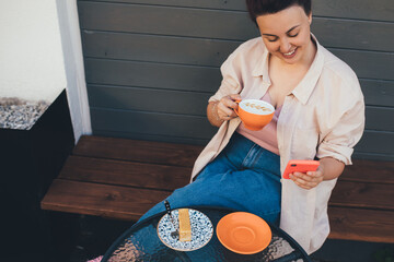 Young woman using smartphone while drinking cofee in a coffeehouse.