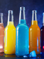 assorted soda pop glass bottles on a blue background. Refreshing summer carbonated lemonades