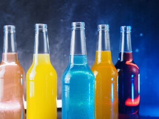 assorted soda pop glass bottles on a blue background. Refreshing summer carbonated lemonades