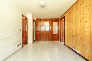 Empty room with white painted walls, another covered with pine wood paneling and stoneware floors