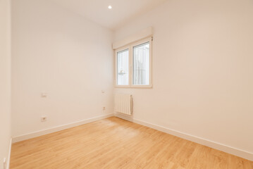 Empty room with plain white painted walls, aluminum window and light oak wood flooring