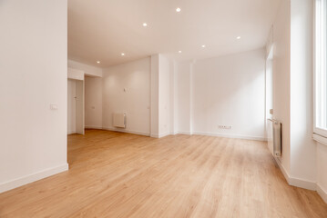 Fototapeta na wymiar An empty room with white painted walls, light oak floorboards and white aluminum radiators