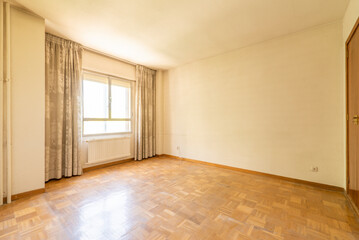 Empty room with light oak floorboards, iron and glass window, metal radiator under the window and gotelet white painted walls