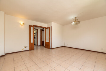 An empty living room with white painted walls, cream stoneware floor, wooden carpentry and glass lamps
