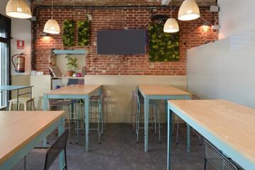 Tall metal and wood tables and chairs in dining room with exposed brick wall