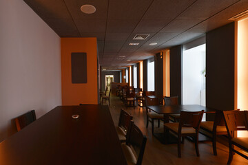 Dining room of a restaurant with wooden tables matching the chairs and neon lights on the walls