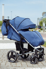 Modern contemporary blue baby stroller with long hood outdoors side view