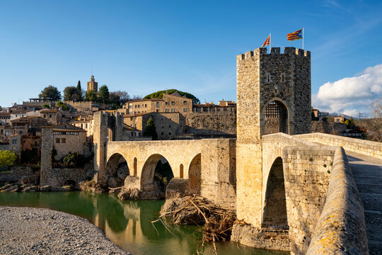 Besalu historic medieval city with Catalonia flags on the stone bridge tower crossing El Fluvia river, Besalu, Catalonia