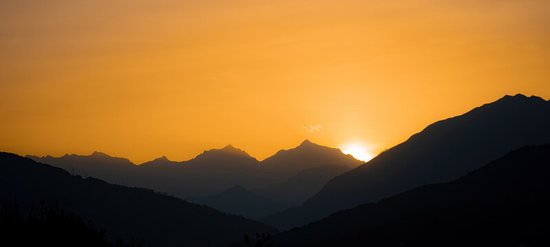 Mountain landscape panorama background - Sunrise with silhouette of mountains and orange sky