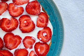 Cake with strawberries and cream on blue plate. Summer Strawberry and Cream sponge Layer Cake on white table cloth background. Top view, copy space. Midsummer food dessert