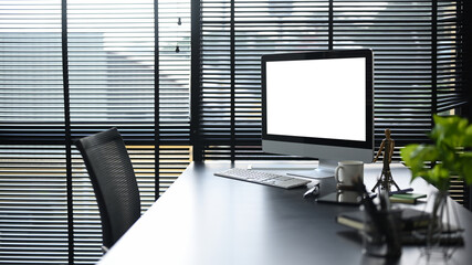 Modern office, computer pc, coffee cup, supplies and houseplant on black wooden table. Empty screen for your advertise text