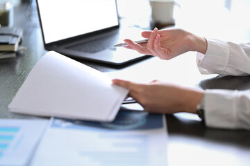 Cropped view of professional businesswoman using laptop and preparing annual financial report at workplace
