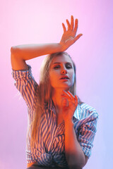 Close-up young girl crushed on glass isolated on pink studio background in neon light. Concept of human emotions, facial expression, youth.