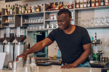 Portrait of an african american male coffee shop owner barista working in a care.
