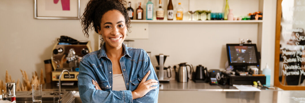 Young black waitress wearing shirt smiling while working at cafe