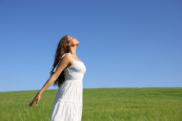 Woman in white dress breathing fresh air in a field