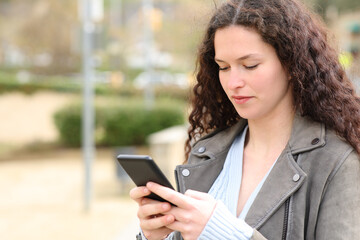 Fototapeta na wymiar Woman texting on cell phone in the street
