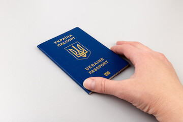 Human hand with Ukrainian international biometric passport closeup on light background. Document used for travel outside Ukraine.