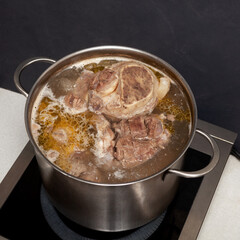 Beef bone broth is cooked in a pot, top view. Bones contain collagen, which provides the body with amino acids, which are the building blocks of proteins
