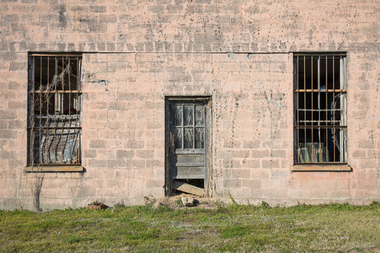 Abandoned jailhouse facade, an empty building with barsont the windows.