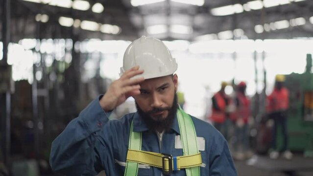 Male engineer or technician worker in safety uniform wearing hardhat and protective eyeglasses walking in the industrial factory. Confident mechanic man working at construction site