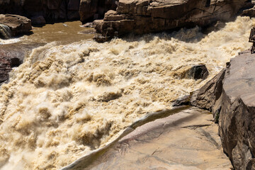 Brown flood water at Augrabies falls in the Oranje river in South Africa. 