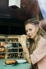Caucasian woman with dreadlocks sitting in cafe.