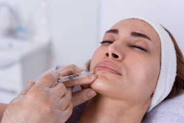 Cosmetologist performs lip filler injections with hyaluronic acid filler in a woman's face Cosmetology female aesthetic in a beauty salon, lip augmentation procedure