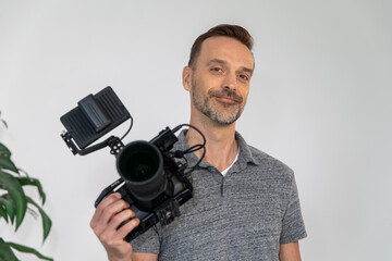 Caucasian Videographer Posing with Video Camera in Hand on Film Set. Camera Man is Proud, Confident and Smiling Looking at Camera