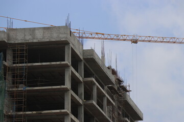 Naklejka premium Construction of the new building with Cranes on the constructing site. Crane and building construction site against the sky