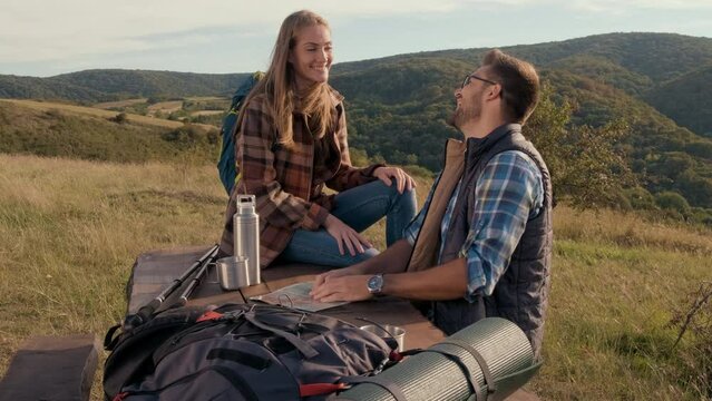 Couple resting after hiking looking for new direction on map.