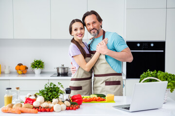 Photo of good mood sweet mature wife husband dressed aprons cuddling cooking lunch indoors home room