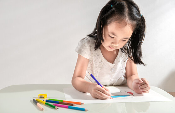 A little toddler girl doing arts and crafts work at home drawing sketching with colorful paint using color pencil. Child education at home during a lockdown. Concept of art and creativity of children