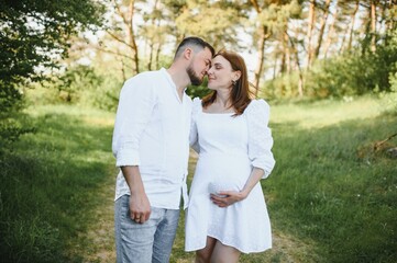Fototapeta premium Happy and young pregnant couple hugging in nature