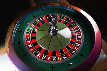 Image with casino roulette wheel with ball on number 0.