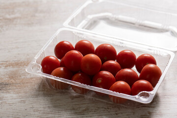 Cherry tomatoes in plastic containers on wooden desk