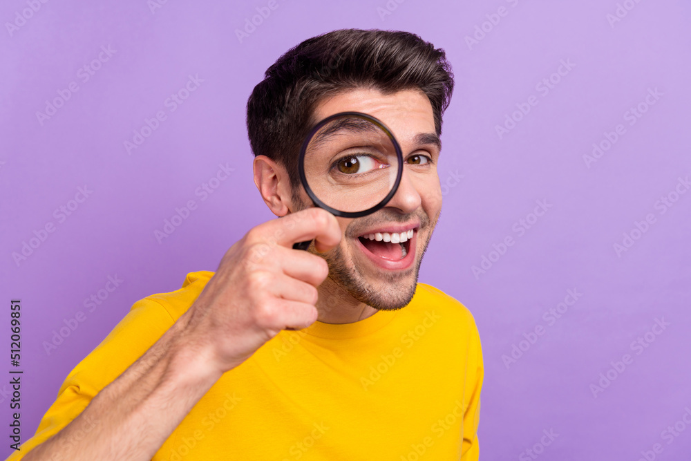 Poster portrait of cheerful laughing man using magnifying glass find investigation isolated on purple color