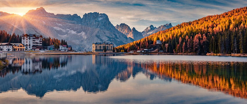 Panoramic autumn cityscape of Misurina village, Italy, Europe. Spectacular sunset on Misurina lake. Impressive evening scene of Dolomite Alps. Traveling concept background.