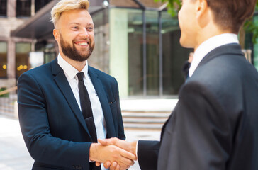 Handshake close-up. Businessman and his colleague are shaking hands in front of modern office...