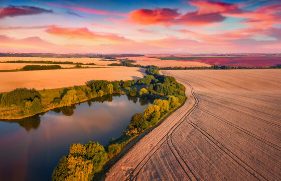 Fantastic summer sunset on outskirts of Ternopil town with small pond. Marvelous evening view from the flying drone of Ukrainian countrysidewith field of wheat.