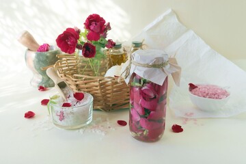 Fresh pink and purple roses, water and sea salt with flower petals, on a light background, natural cosmetics, body care, love emotion