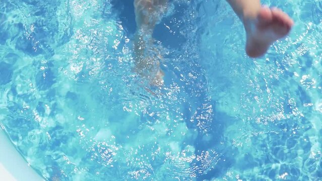 child playing with his feet in the pool kid swimming in the pool summer vacation blue water splash learns to swim
