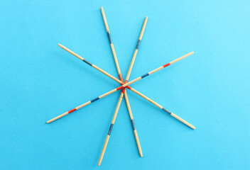 Mikado game over blue background. Wooden sticks that create a graphic image and a geometric frame
