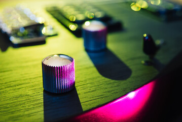 Details of the body and fretboard of an electric guitar. Stage lighting, light music. 