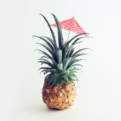 Image with ripe pineapple with parasol over white background. Summer holidays and tropical theme. vintage filtered