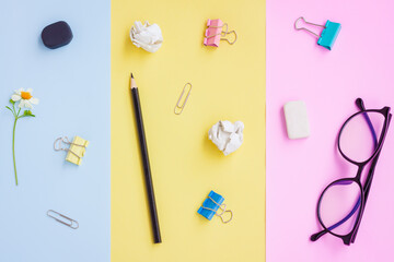 Black Pencil,Eraser,Paper Clips,Eyeglasses and White Flower on Pink,Yellow and Blue Background,...