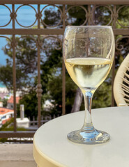 Beautiful wineglass with white wine, standing on the table  against the backdrop of sea. Side view, close-up. Concept of leisure and travel