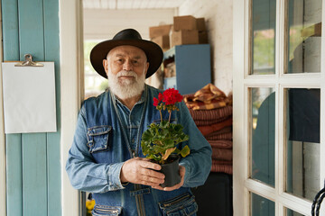 Happy aged man buying flower in pot in boutique